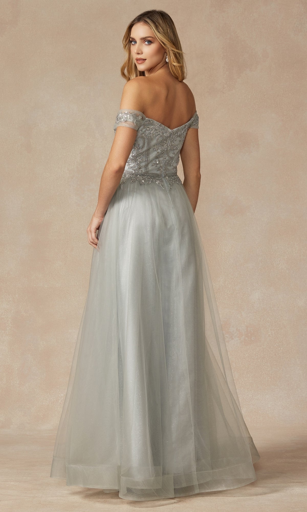 Woman wearing the Long Sweetheart Prom Ball Gown: Juliet 287 in light gray, featuring an off-the-shoulder design and beaded corset bodice, stands looking over her shoulder against a neutral background.